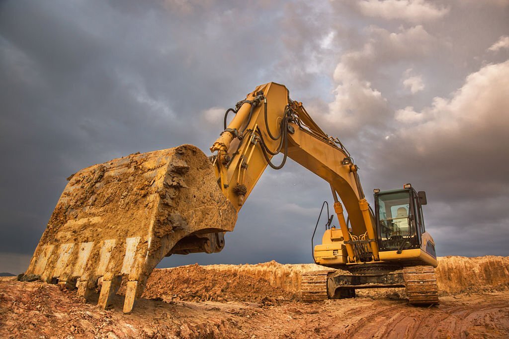 Big excavator with dramatic sky at sunset